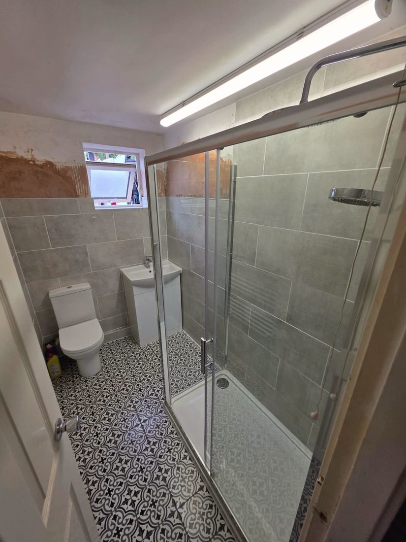 Finished bathroom with grey tiling, walk-in shower and patterned floor tiles