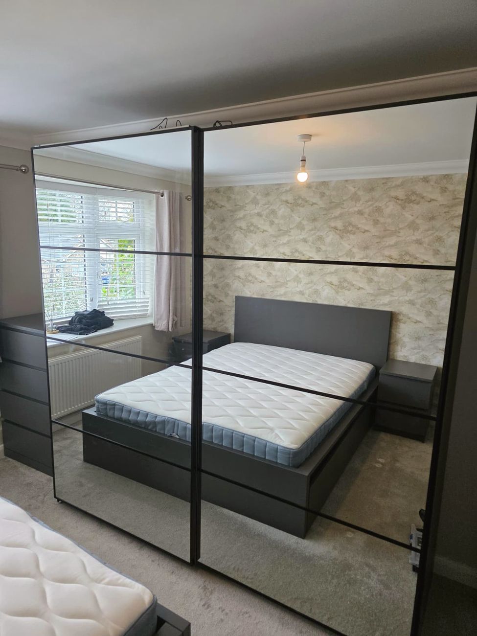 Fitted bedroom with mirrored sliding wardrobes, bed frame and bedside tables