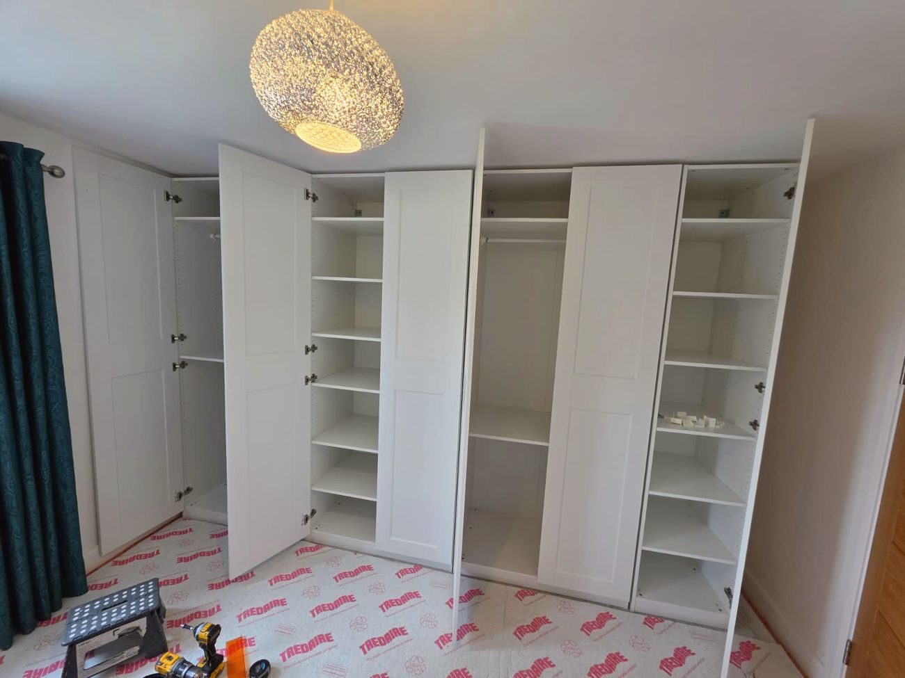 A run of fitted white wardrobes across a bedroom wall