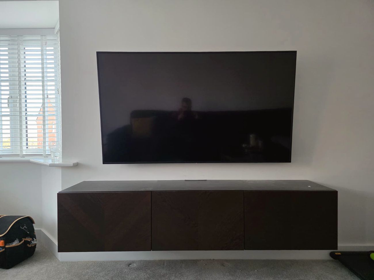 Wall-mounted TV above a dark wood floating media unit