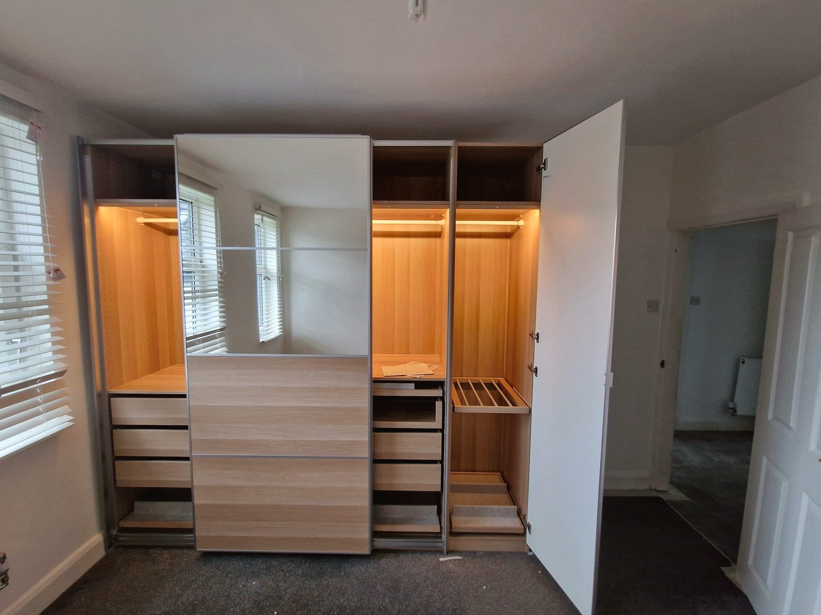 An assembled IKEA PAX wardrobe with sliding mirror door, internal drawers and shelving
