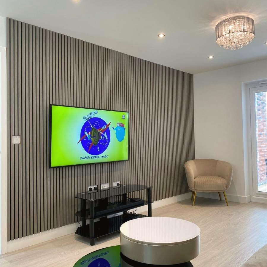 A wall-mounted TV on a slatted acoustic feature wall with downlights