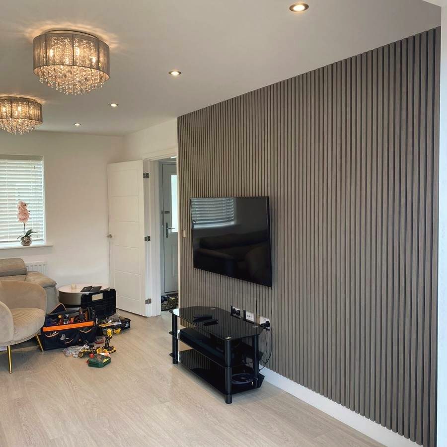 A flat-screen TV mounted on a slatted feature wall, work in progress