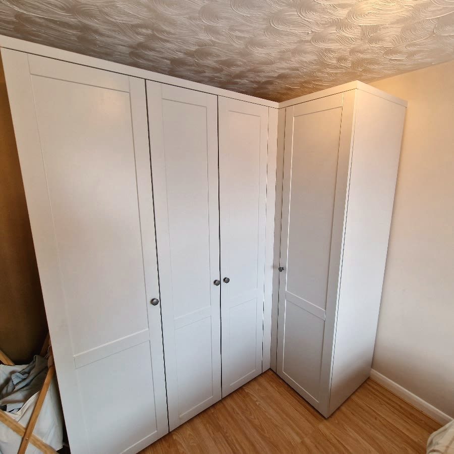 A fitted white corner wardrobe with shaker-style doors