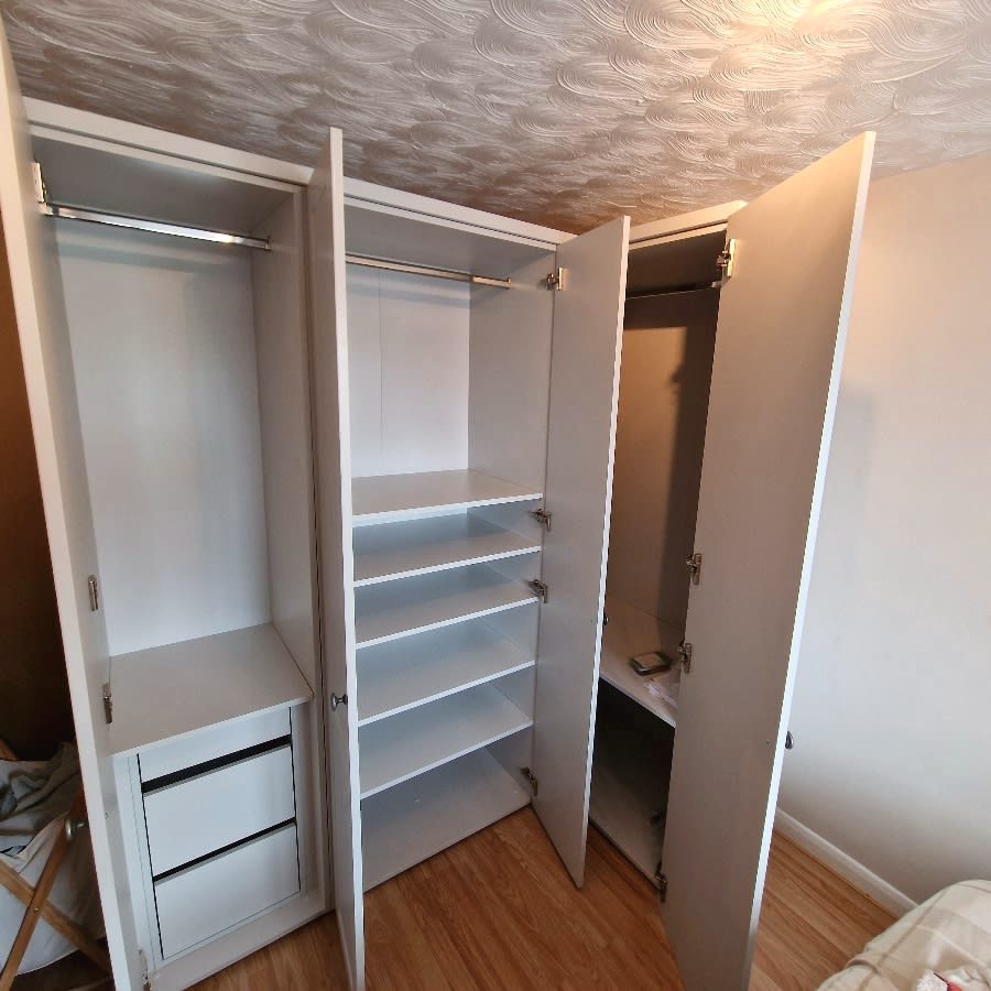 Inside of the white corner wardrobe showing shelves, rails and drawers